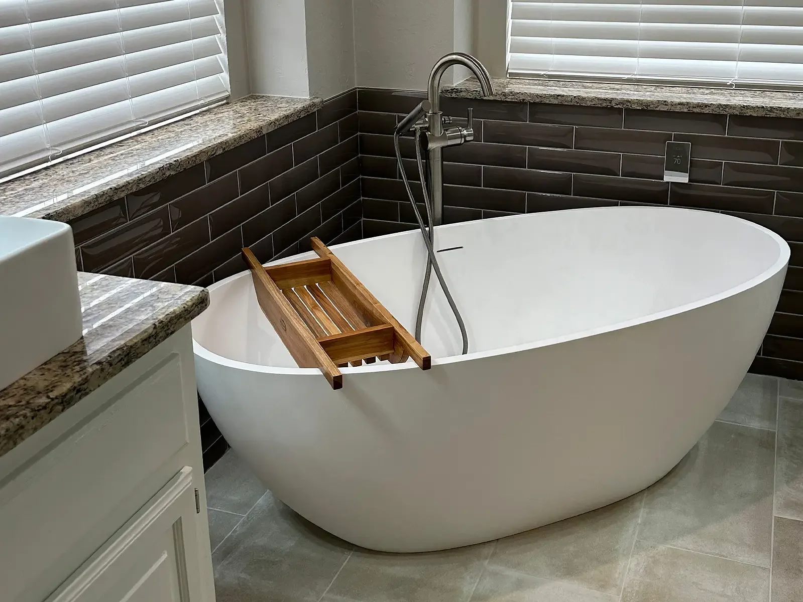 Freestanding bathtub in a newly renovated bathroom with new tile floors and backsplash.