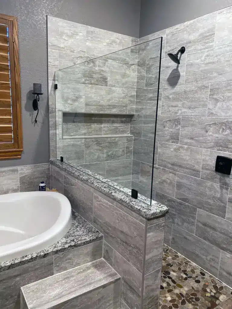 Bathroom tile installation remodel showing off new free-standing shower with glass wall and ceramic tub.