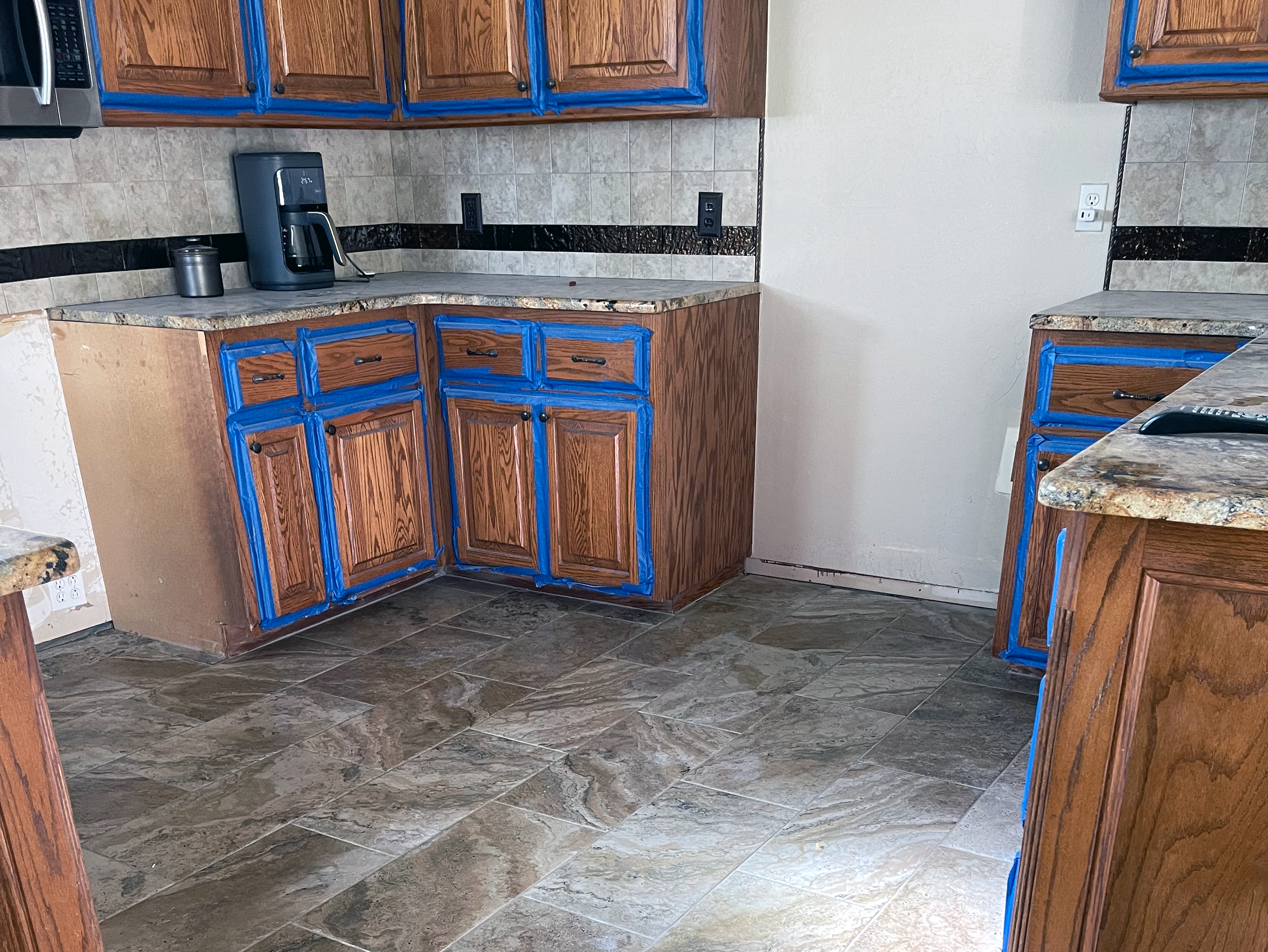 A kitchen in the middle of a remodel with cabinets taped off and tile installed.