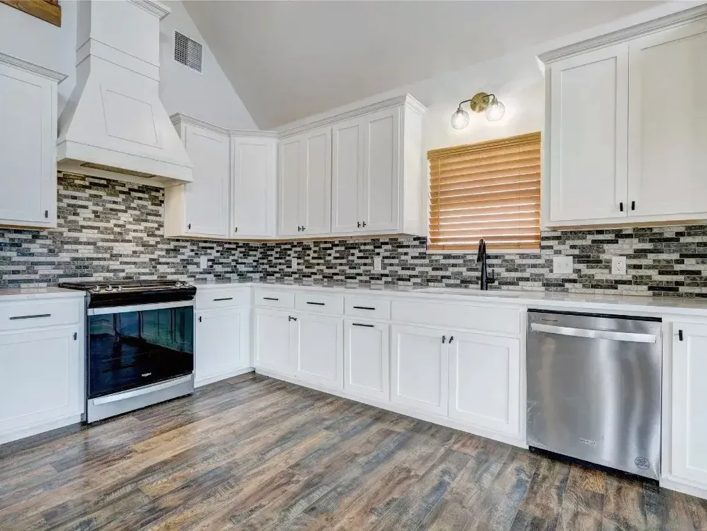 Kitchen with white cabinets and new tile backsplash and tile flooring.