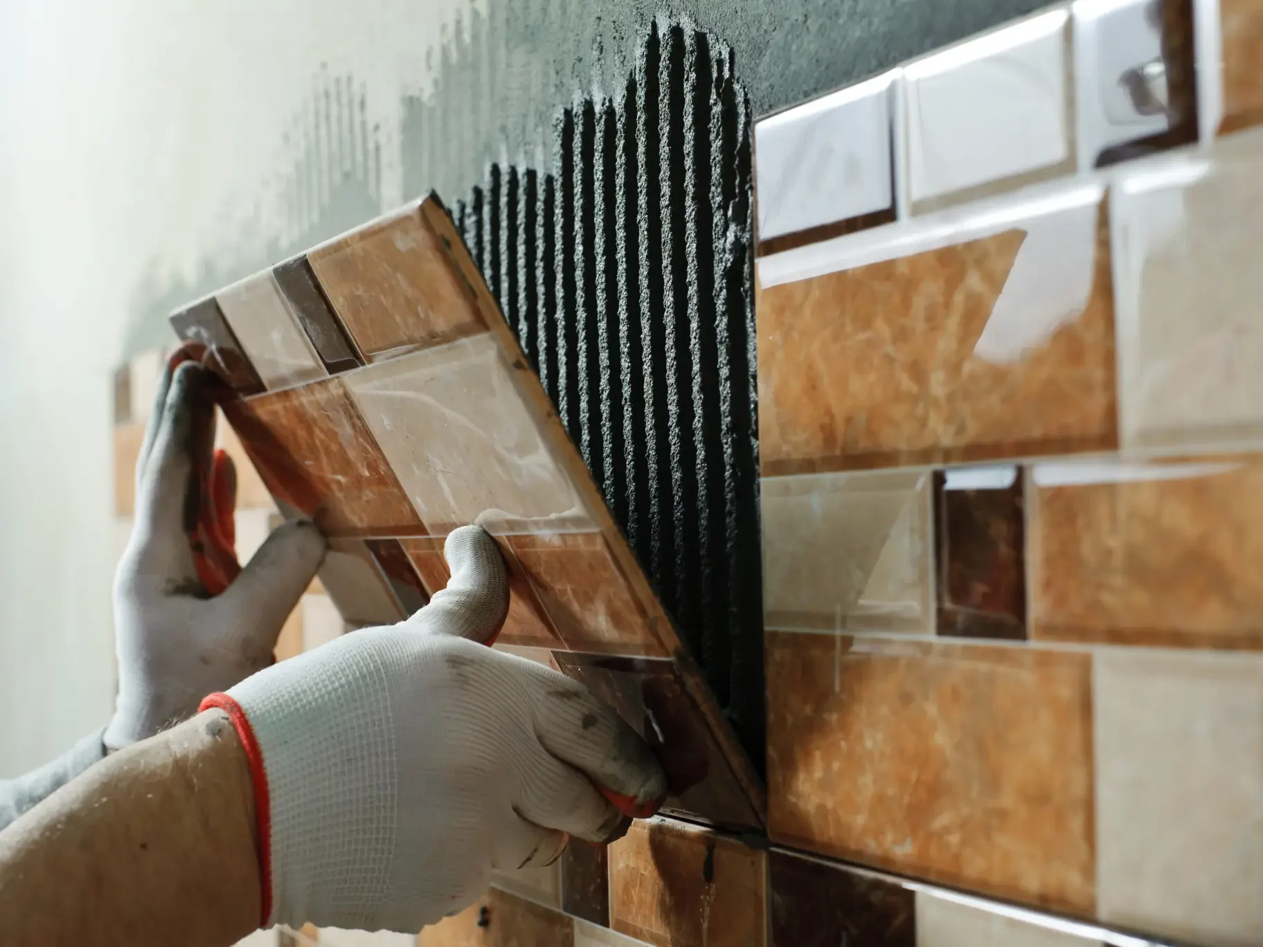 Tile installer places a piece of tile on a wall