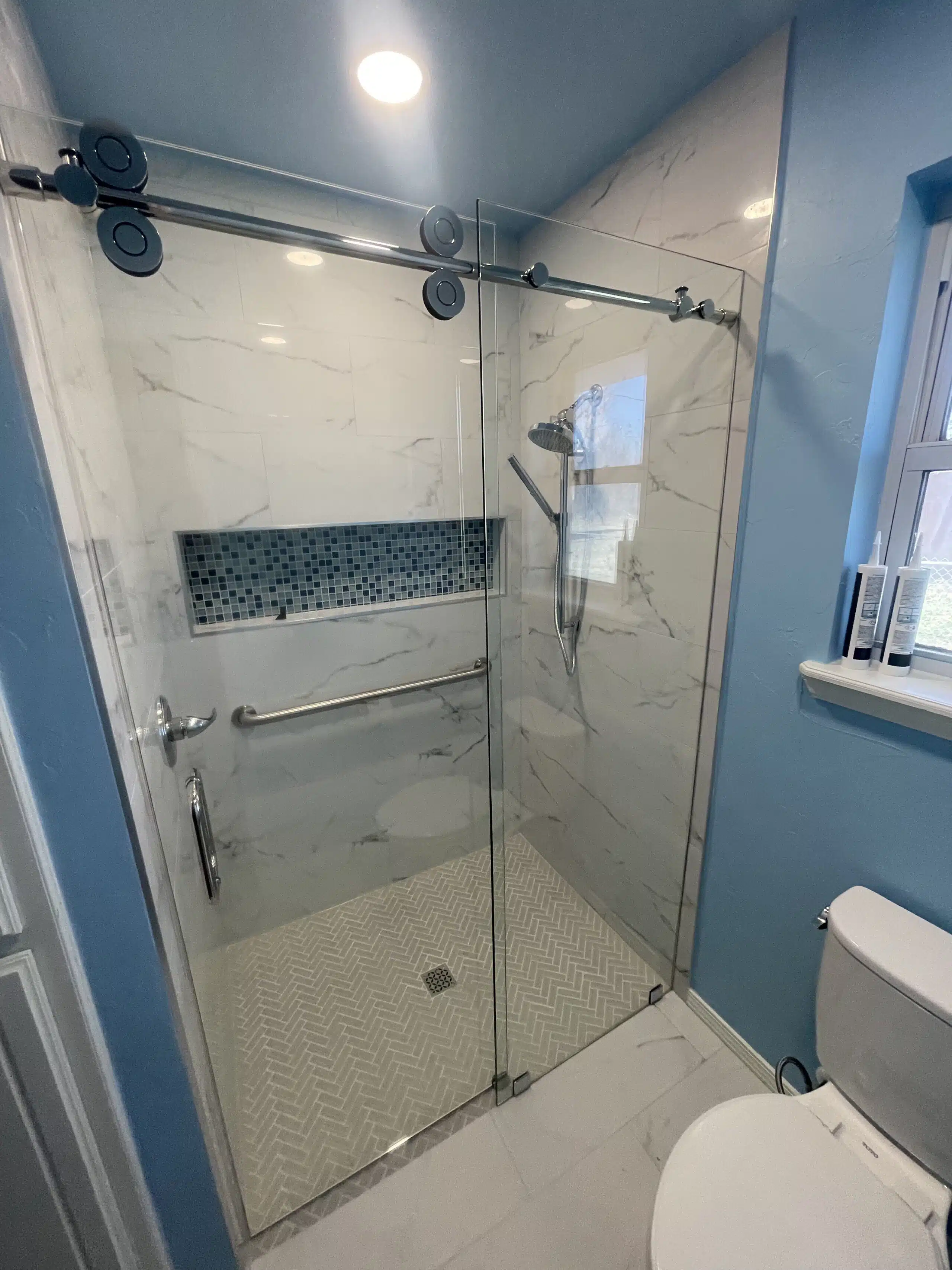 Alternate view of bathroom completed work, after pic with blue walls, new stand-up shower, and new white toilet.