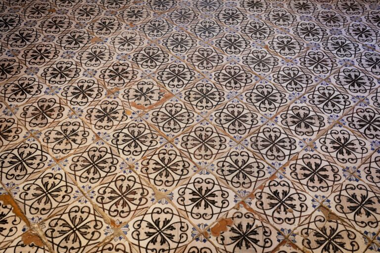 An off-white tile floor with looped black patterns shows off its age, chipping around the edges.