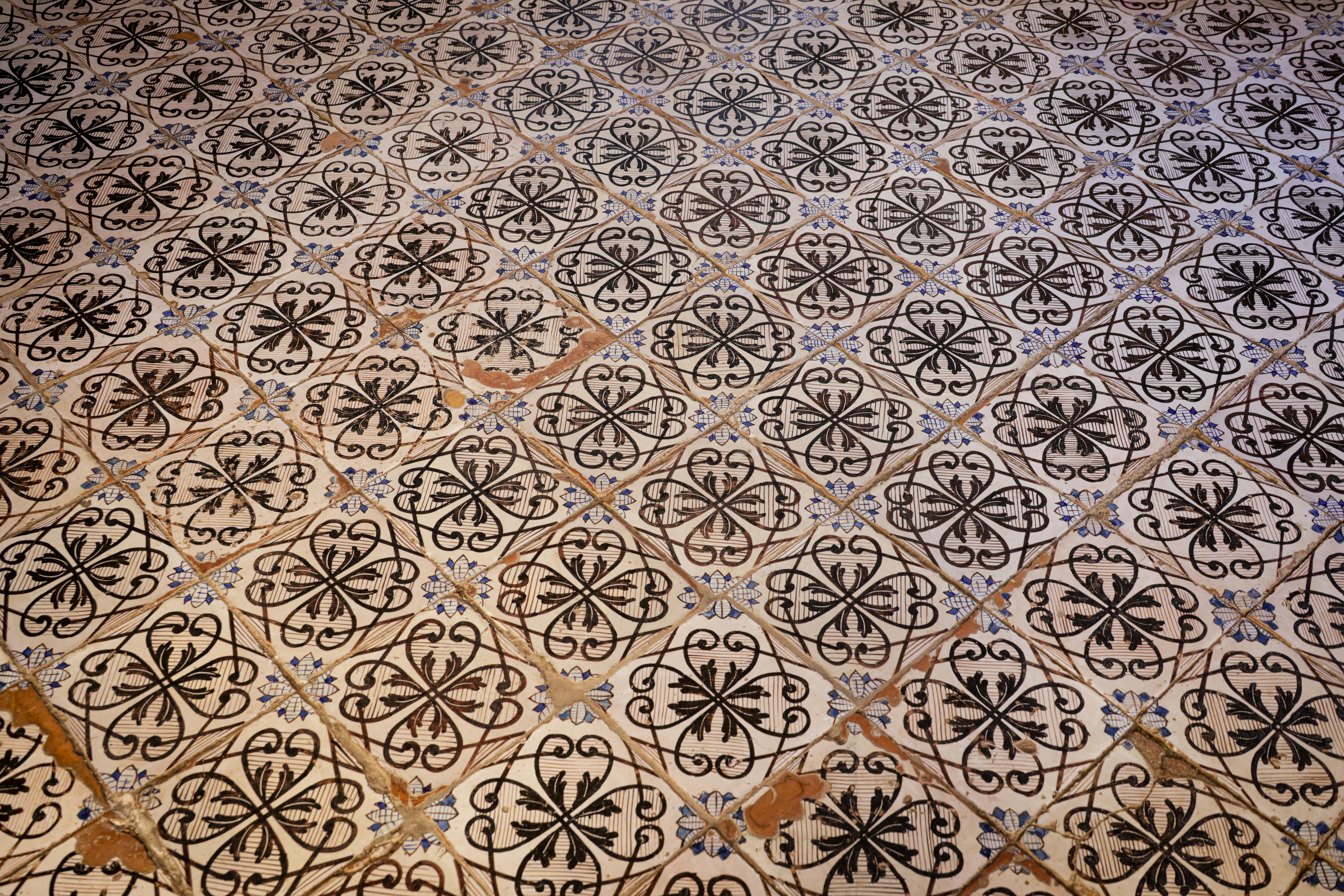 An off-white tile floor with looped black patterns shows off its age, chipping around the edges.